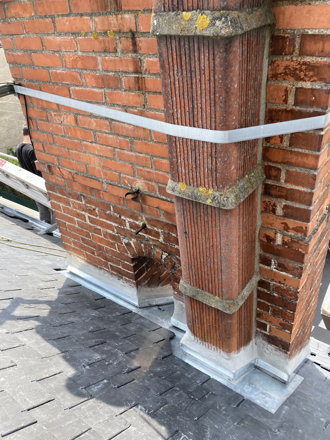 Détail du zinc façonné autour d’une cheminée en briques