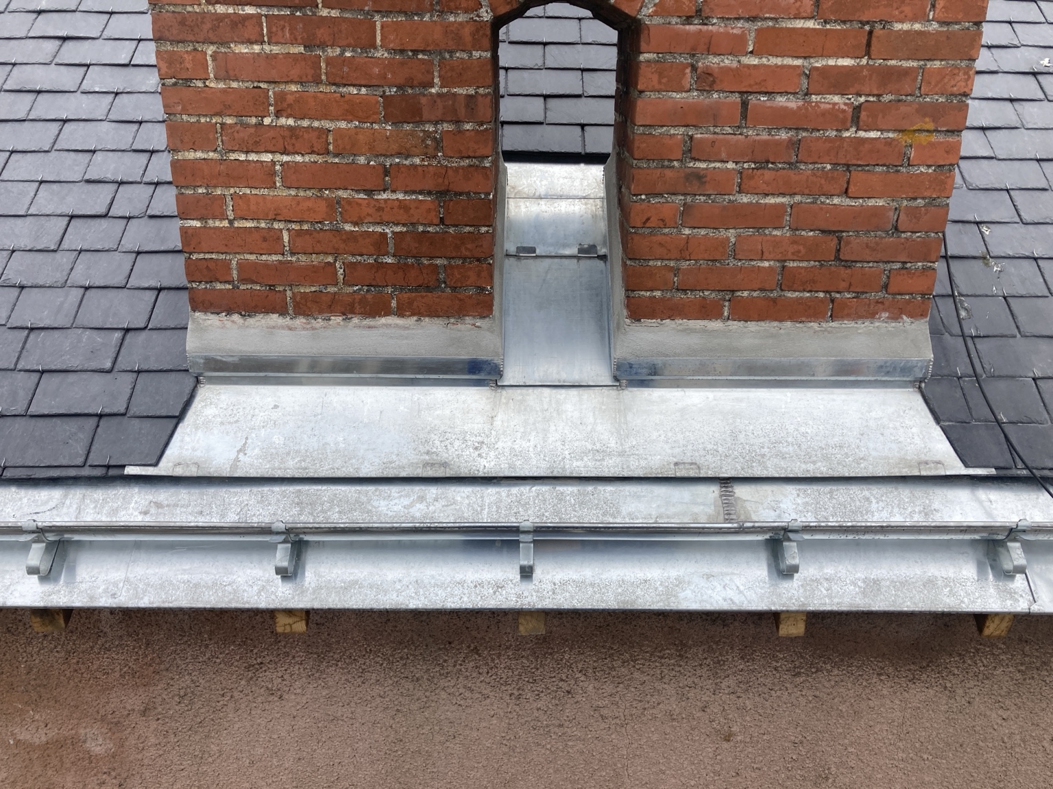 Vue de face du raccord en zinc au pied de la cheminée